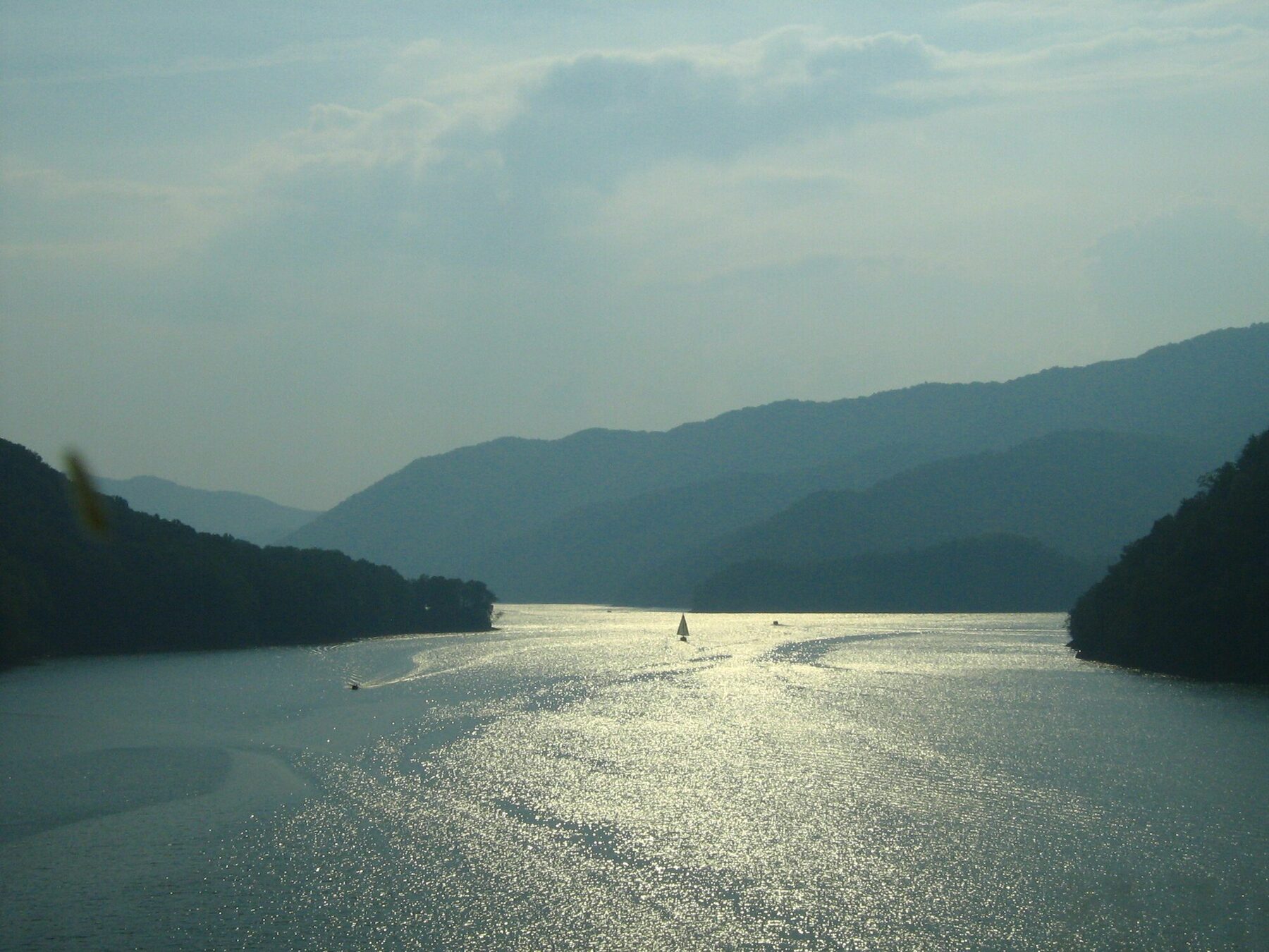 Sailboat on Watauga Lake with layered mountain ridges behind