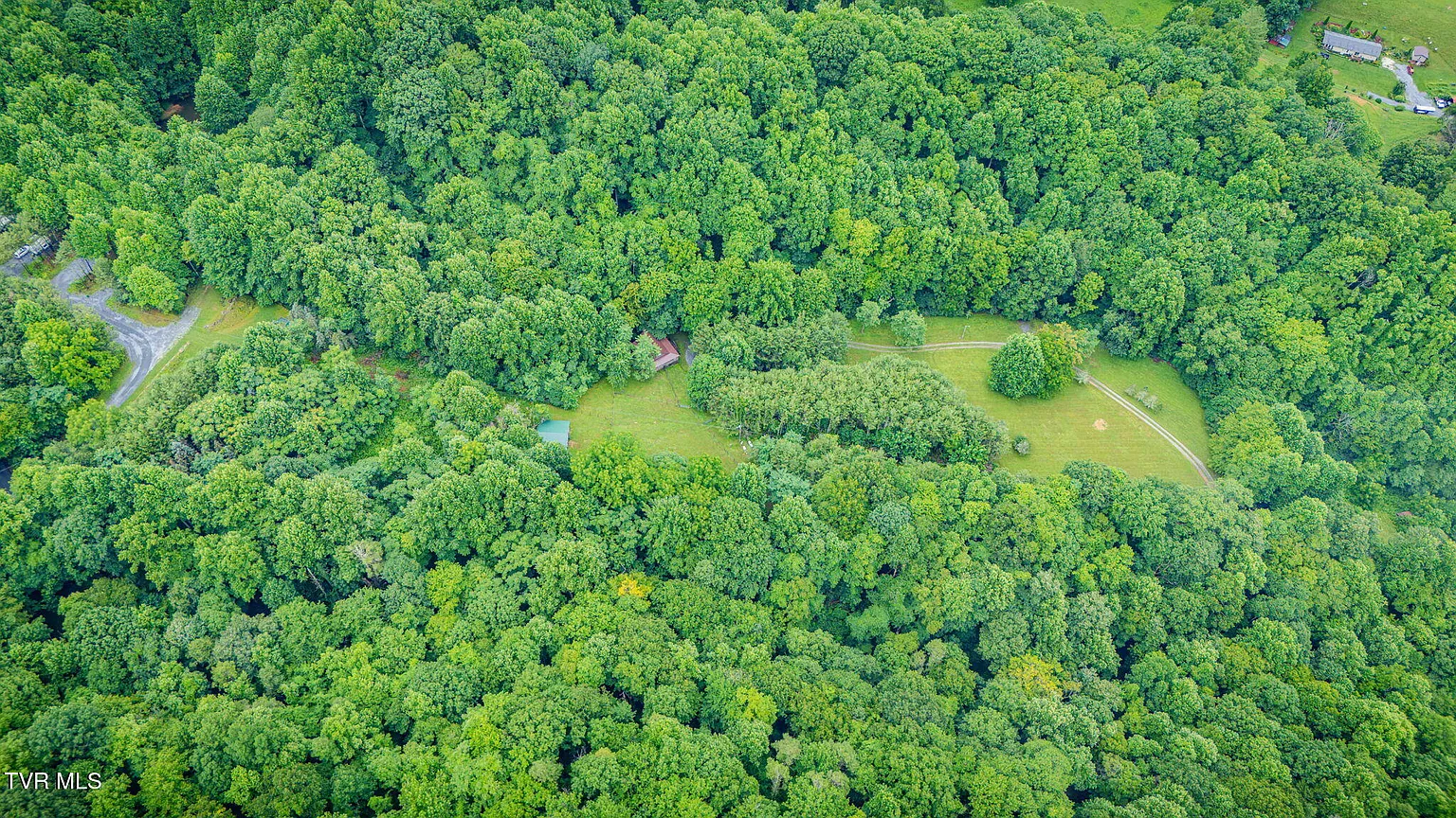 Wide aerial of forested property with meadow clearing
