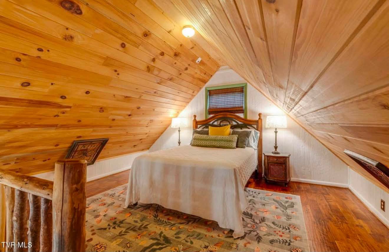Bear cabin loft bedroom with quilted bed under wood-paneled ceiling